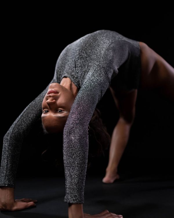 Woman performing a graceful yoga pose in a calm, dark studio.